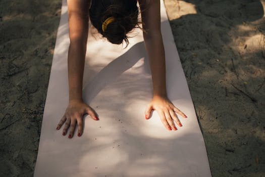 A woman exercises on a yoga mat in outdoor sunlight, promoting fitness and relaxation.