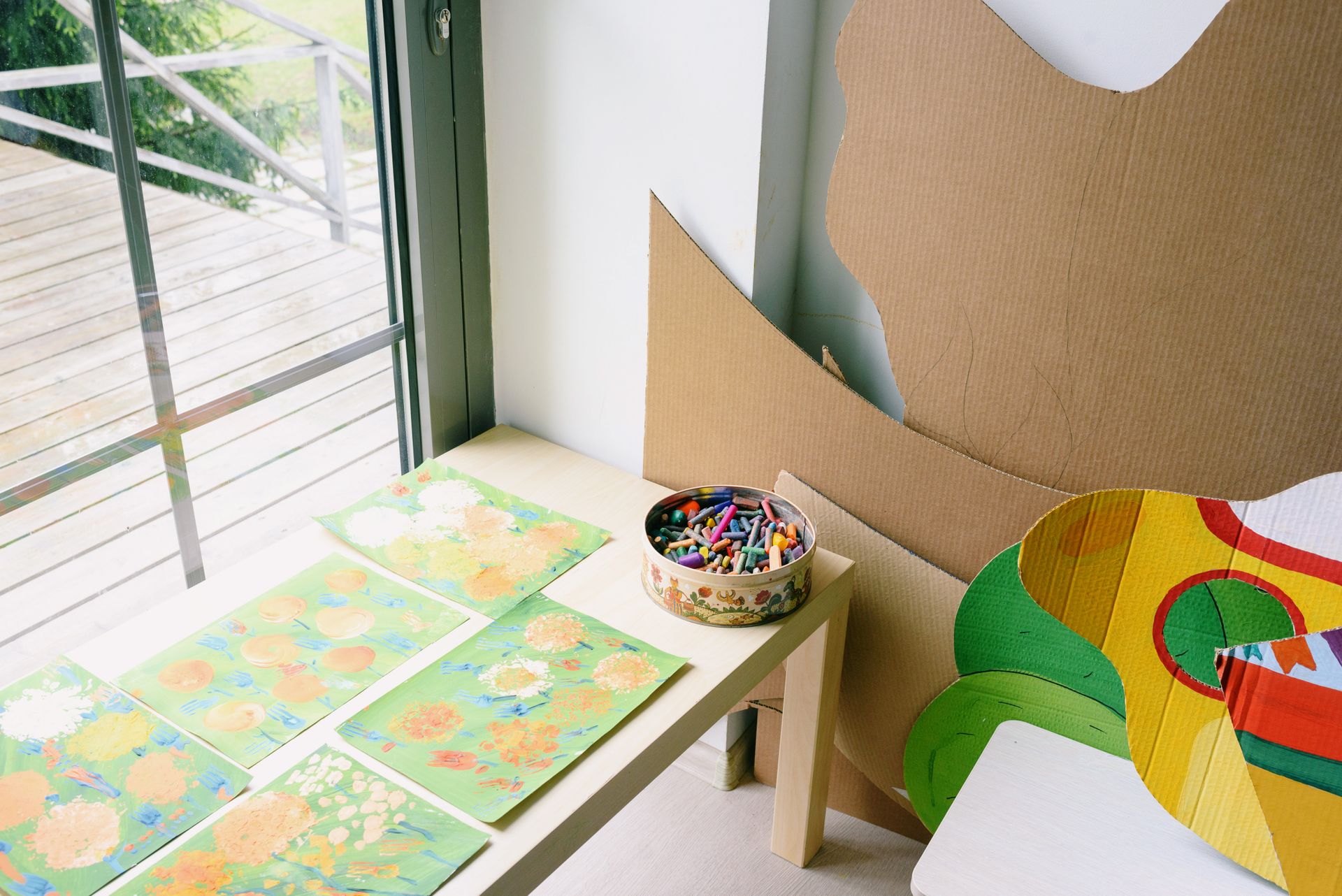 A creative space featuring children's artwork, colored crayons, and cardboard crafts by the window.