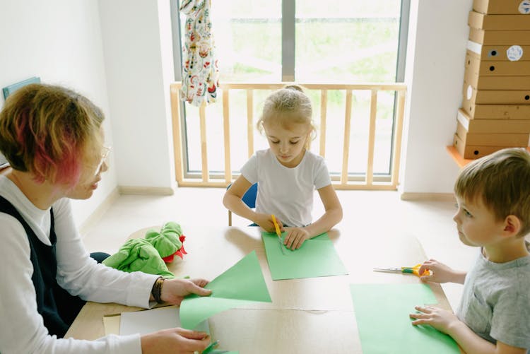 Mother And Children Sitting And Cutting Paper