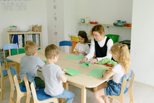 Children and teacher engage in a craft session using paper and scissors in a kindergarten classroom.