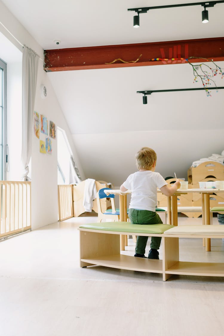 Back View Of A Blond Kid Sitting On A Wooden Chair 