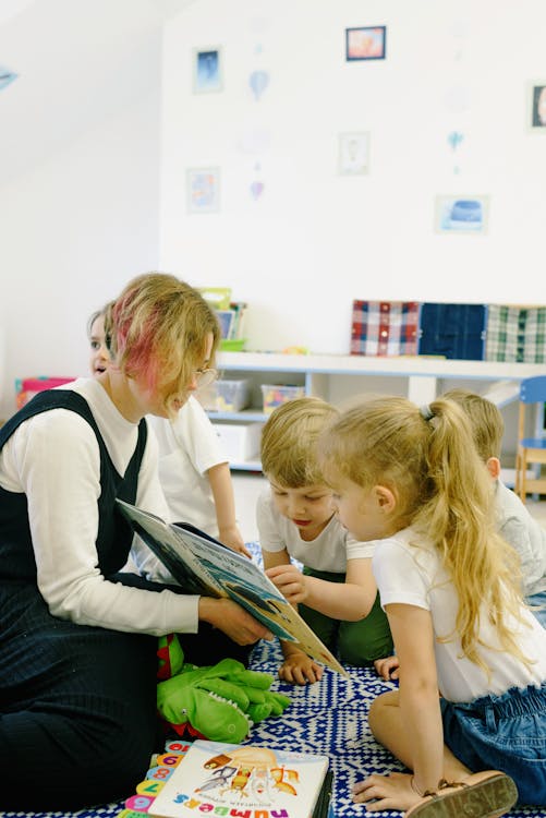 Free Children in the School Reading a Book with a Teacher Stock Photo