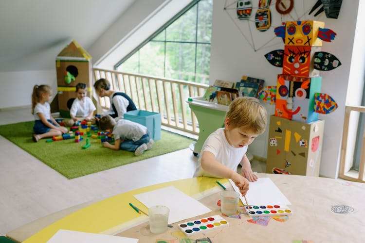 A Kid Painting On The White Paper With Watercolor