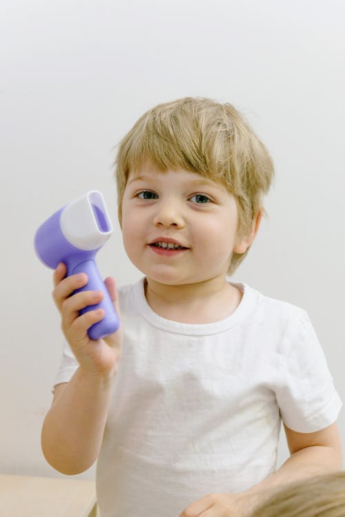A Boy with Blonde Hair Holding Purple Plastic Toy