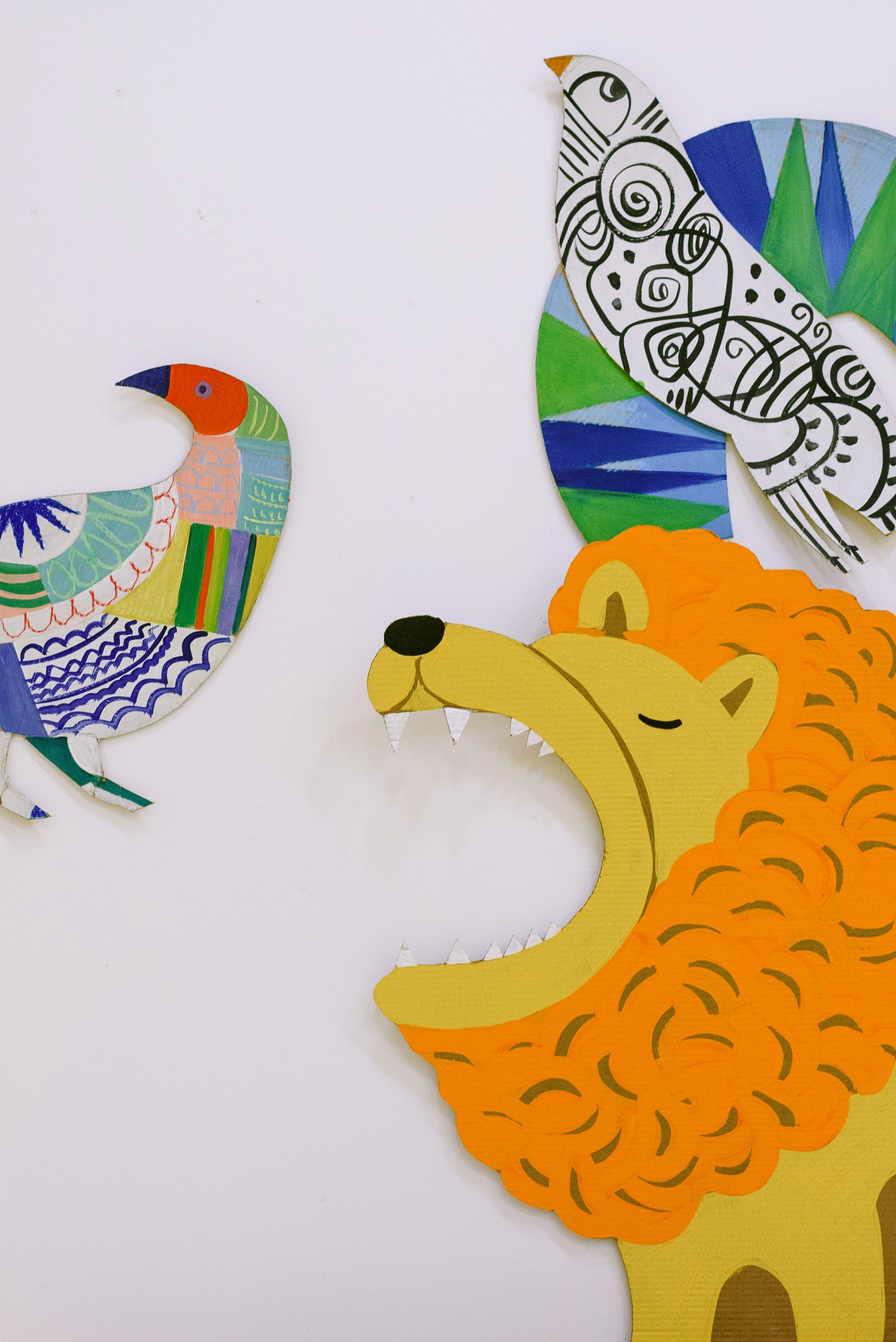 Vibrant paper cutouts of a lion and birds in artistic design.
