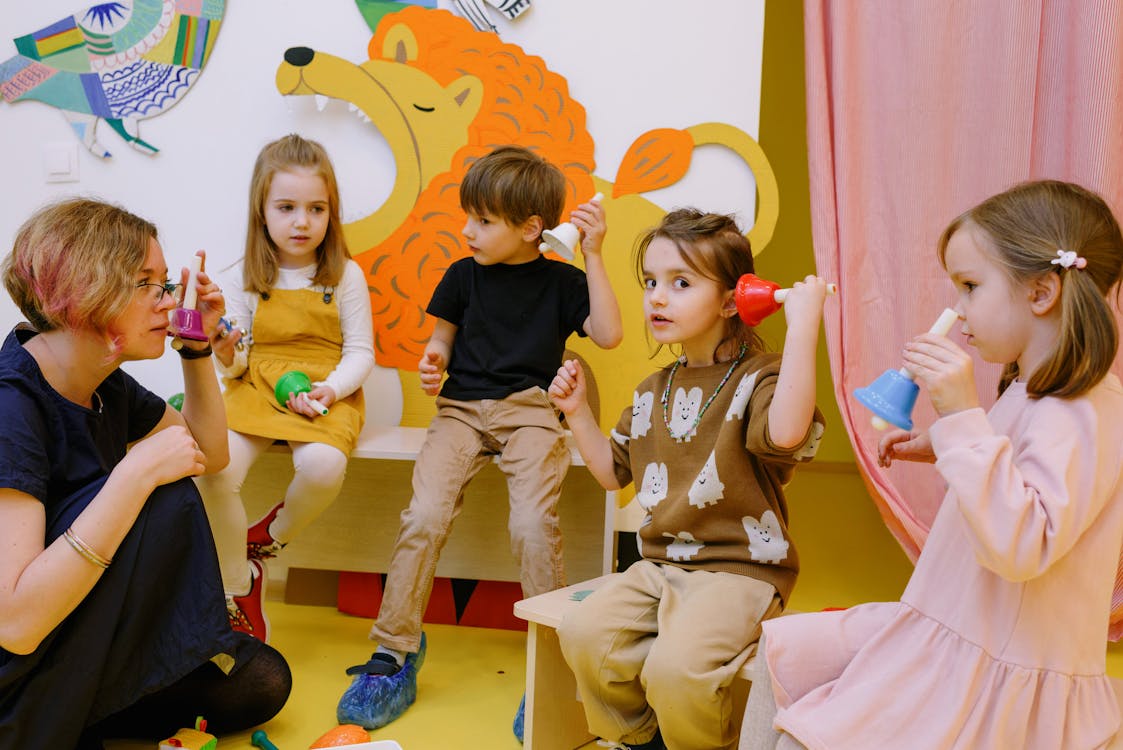 Free Children with Her Students Holding Different Color Bells Stock Photo