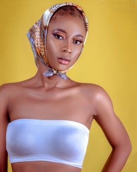 Portrait of a woman in a colorful headscarf against a yellow background, radiating confidence.