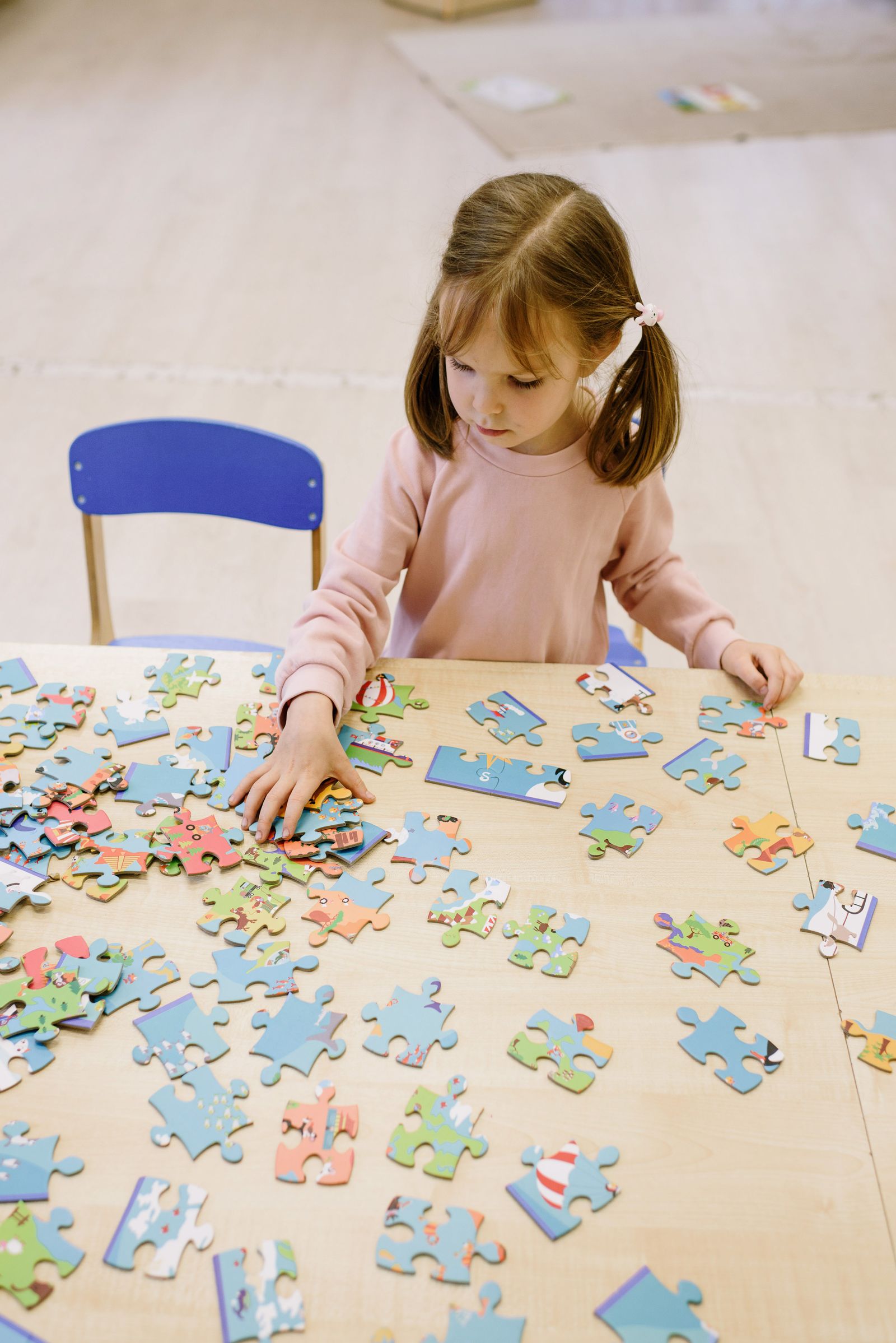 A child concentrating on a colorful puzzle at a play table
