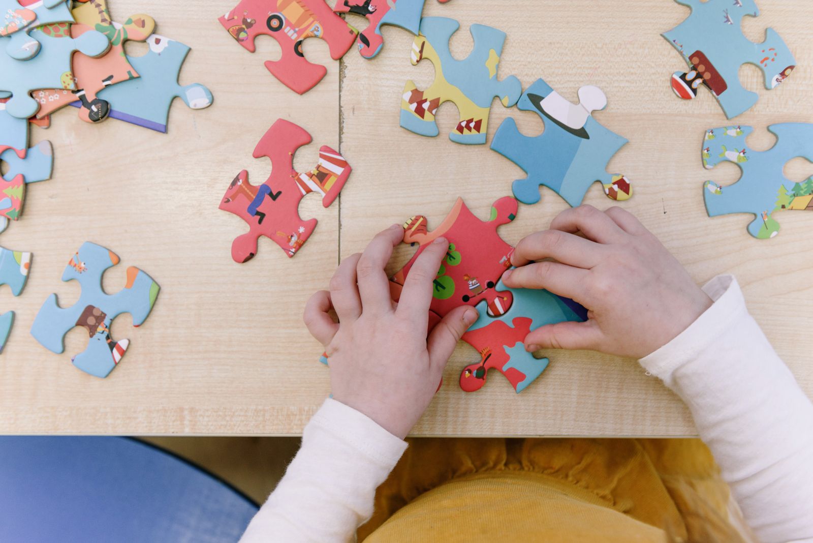 Close-up of a child assembling colorful puzzle pieces on a wooden table