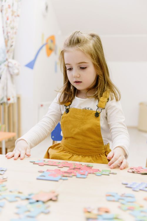 Free A child focused on solving a colorful puzzle at home. Stock Photo