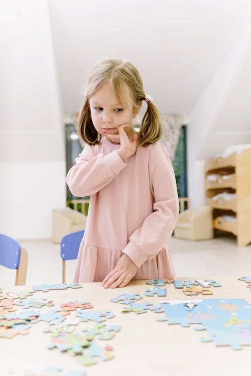 Free Girl in Pink Dress Playing With Puzzle Stock Photo