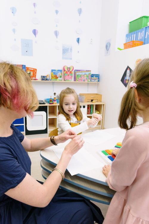 Free Children creating with modeling clay in a bright classroom setting with a teacher assisting. Stock Photo