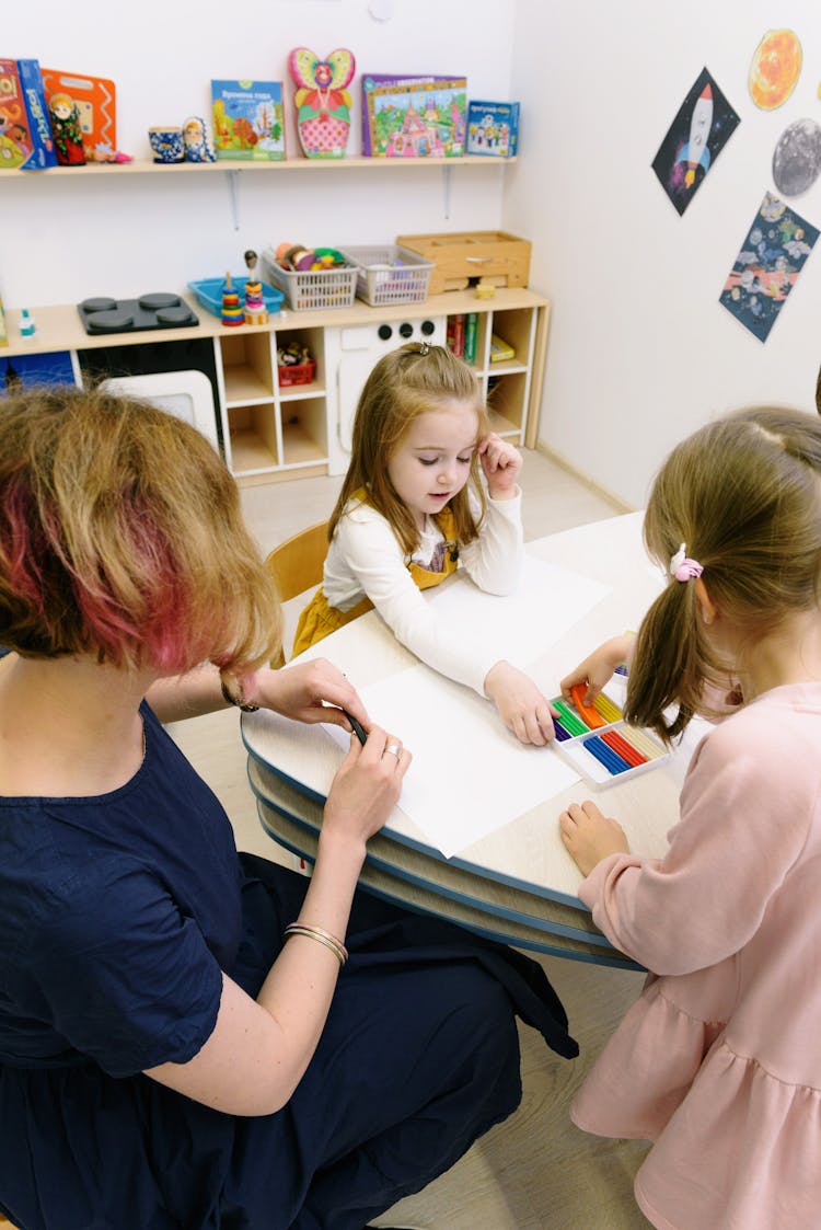 Two Girls And A Woman In Dark Blue Dress Using Modeling Clay