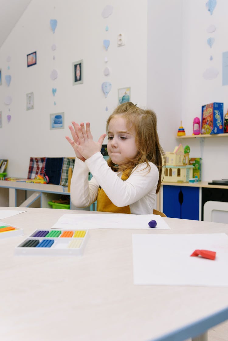 Girl Sculpting Of Modeling Clay While Sitting At Table