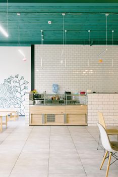 Bright modern café interior with white tiles, colorful ceiling, and minimalist furniture.