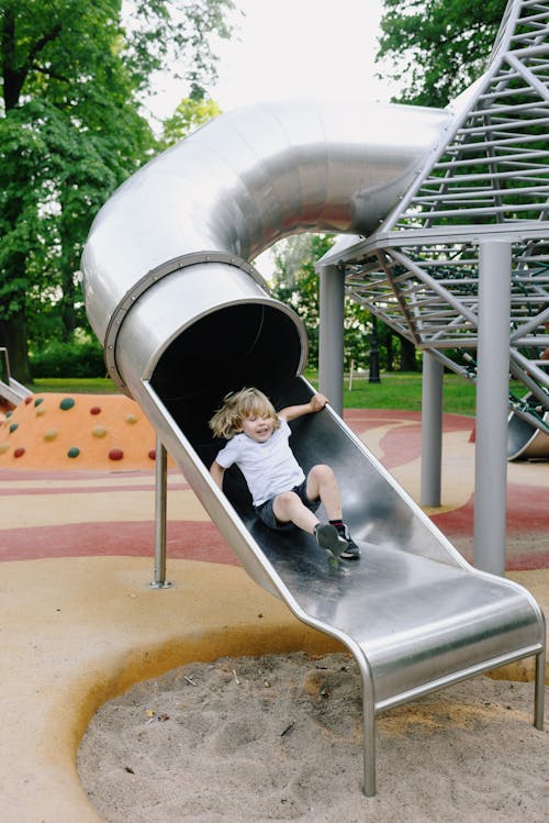 Free Boy Sliding Down on Playground Stock Photo