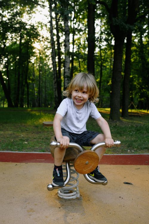 Free Young boy enjoying a ride on a seesaw in a sunny park setting. Stock Photo