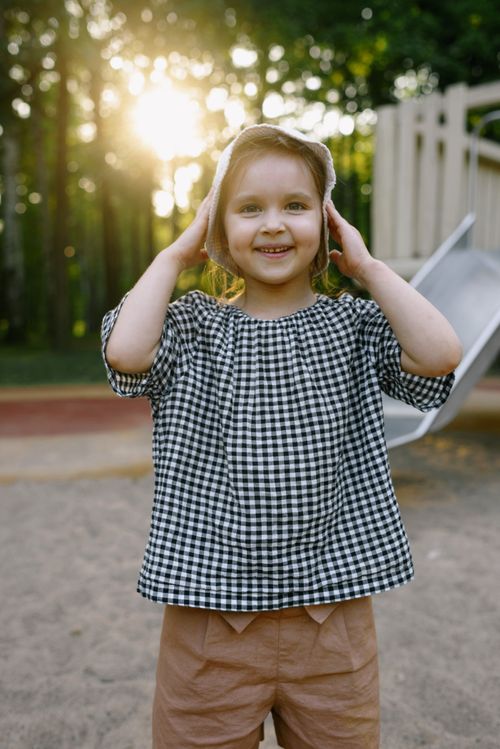 Free Cheerful young girl in checkered top enjoying a sunny day at the playground. Stock Photo