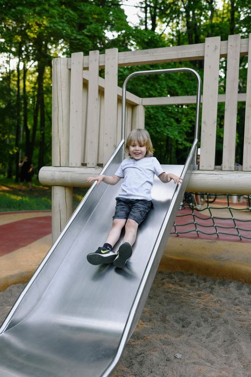 Free A happy child enjoying a sunny day sliding down a playground slide. Stock Photo