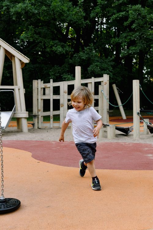 Free A joyful child runs across a vibrant playground in summer, full of energy and excitement. Stock Photo