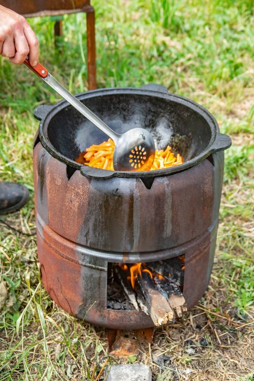 Free A rustic outdoor cooking scene with frying in a pot over an open fire using firewood. Stock Photo