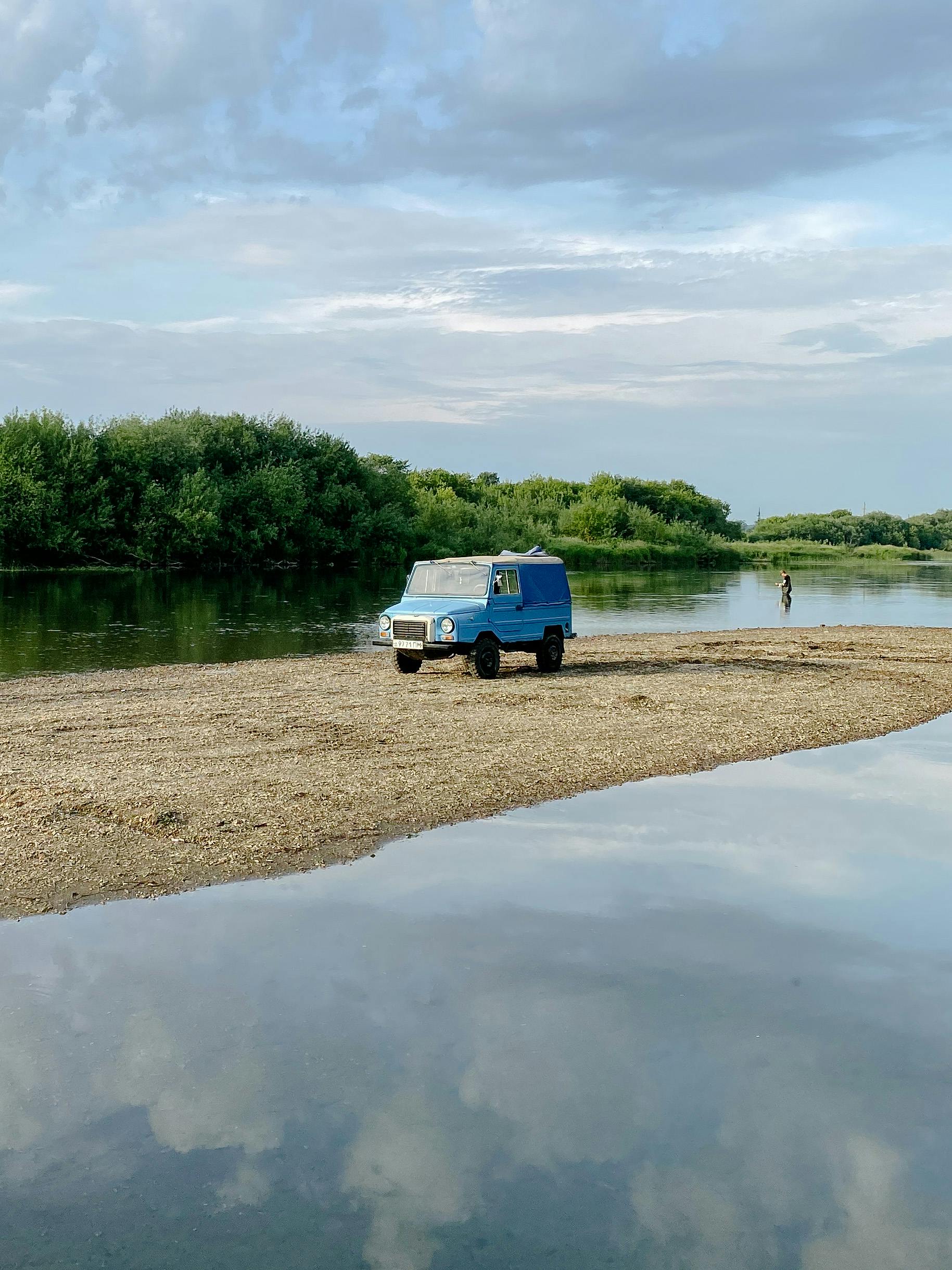 Explore scenic landscapes with a vintage van on a sandy riverbank, perfect for travel enthusiasts.