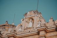 Brown Church with Statues Under Blue Sky