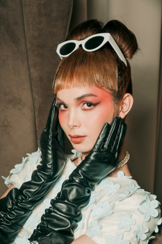 Retro-inspired portrait of a fashionable woman with sunglasses and gloves, showcasing bold makeup.