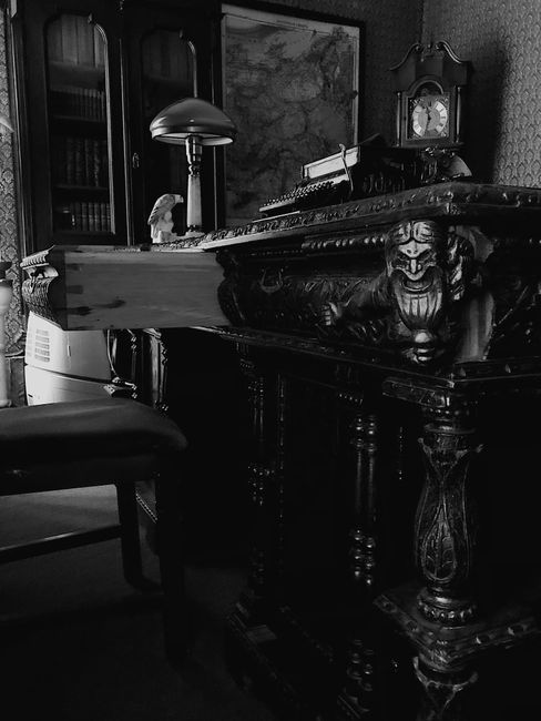 Elegantly carved vintage desk in a historic study with detailed ornaments and classic furniture.
