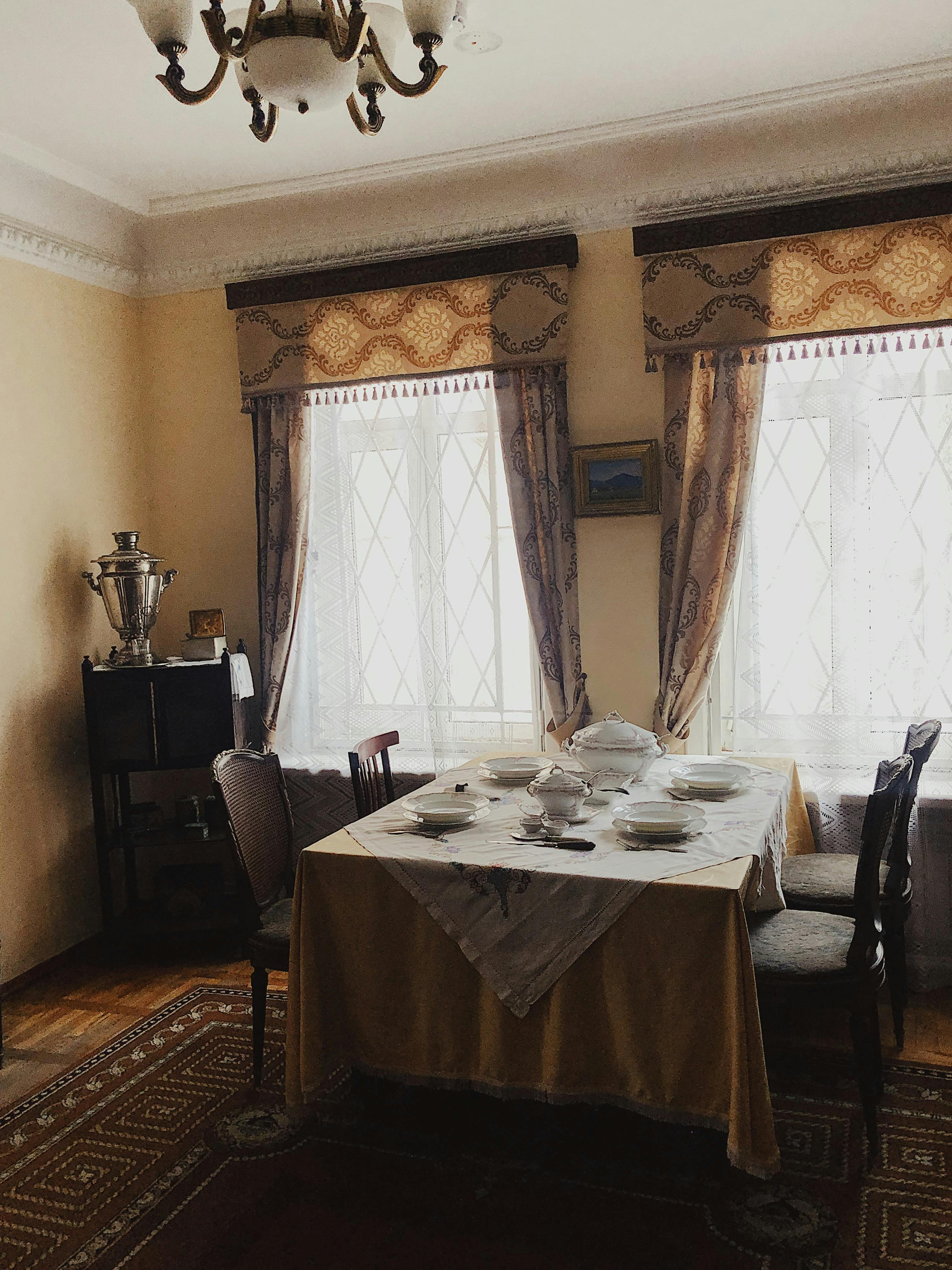 Elegant dining room featuring vintage decor, classic curtains, and a beautifully set table for a cozy indoor ambiance.