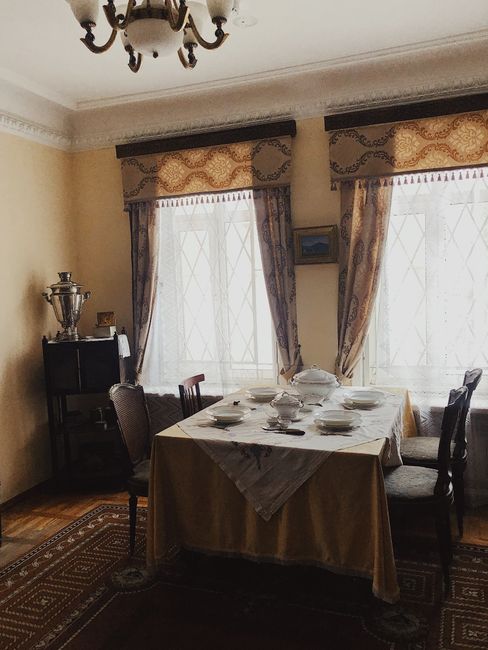 Elegant dining room featuring vintage decor, classic curtains, and a beautifully set table for a cozy indoor ambiance.