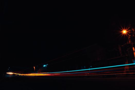 Dynamic light trails captured at night on a city street, showcasing urban energy.