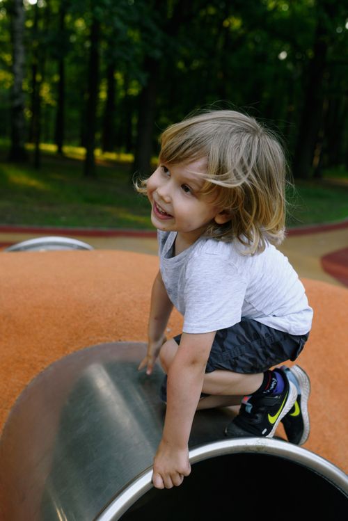 Free A smiling child having fun climbing in a playground during a sunny summer day. Stock Photo