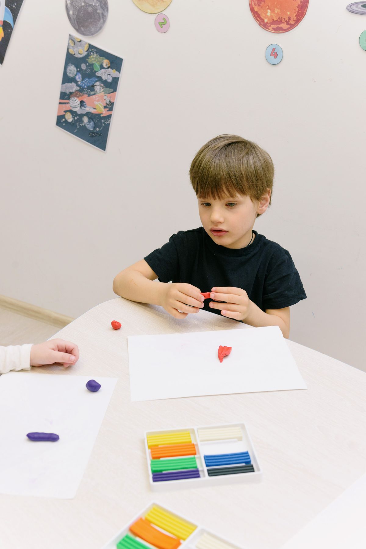 Young boy shaping clay with his hands during a classroom art session