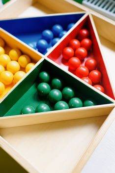 Close-up of colorful balls arranged in a triangular wooden toy, ideal for educational games. — photo by Ksenia Chernaya