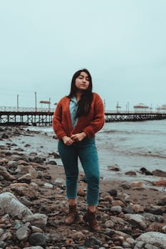 Confident woman in casual fashion standing on a rocky shore in Trujillo, Peru.