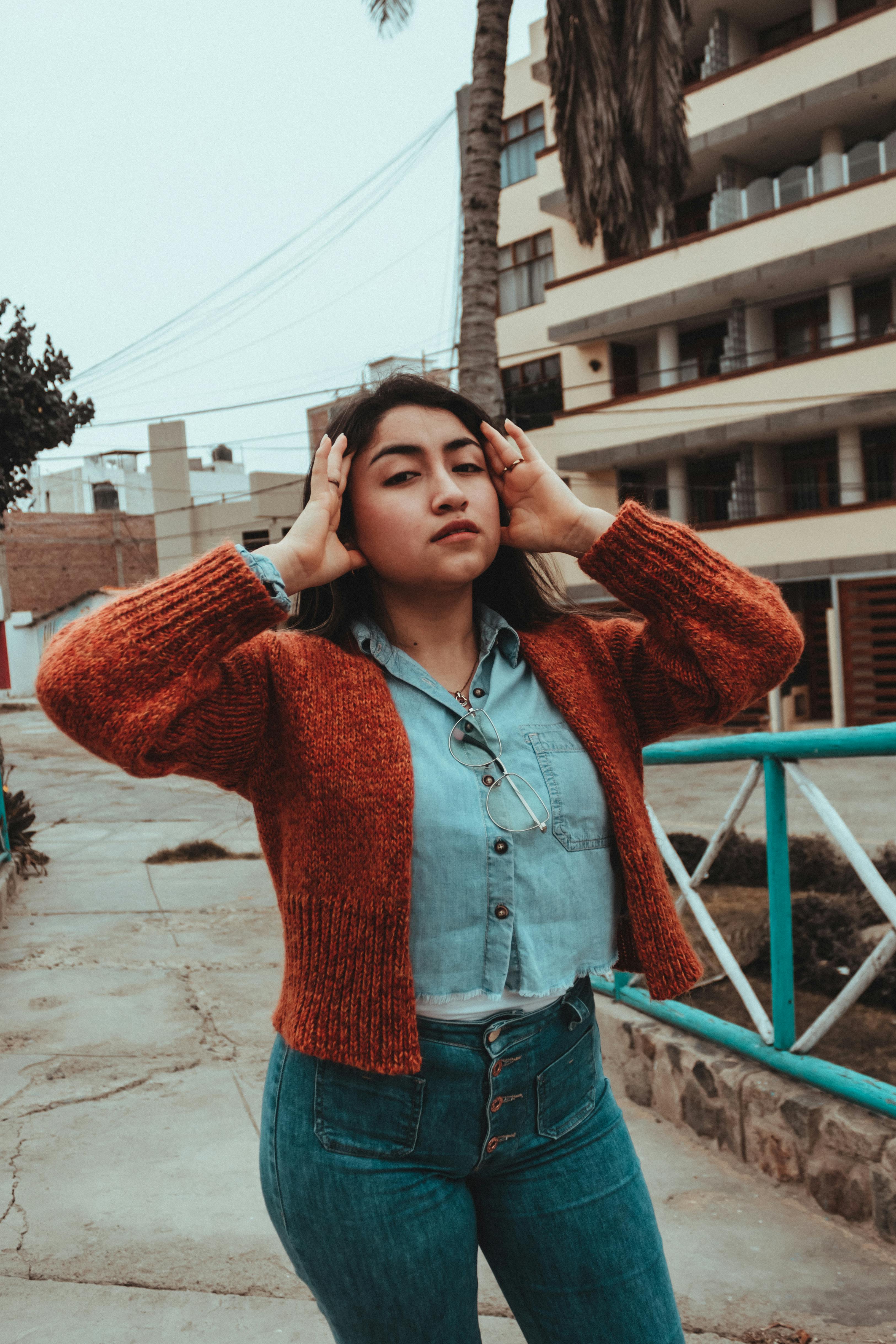 Stylish woman poses in a knitted sweater in an urban setting, exuding modern style.