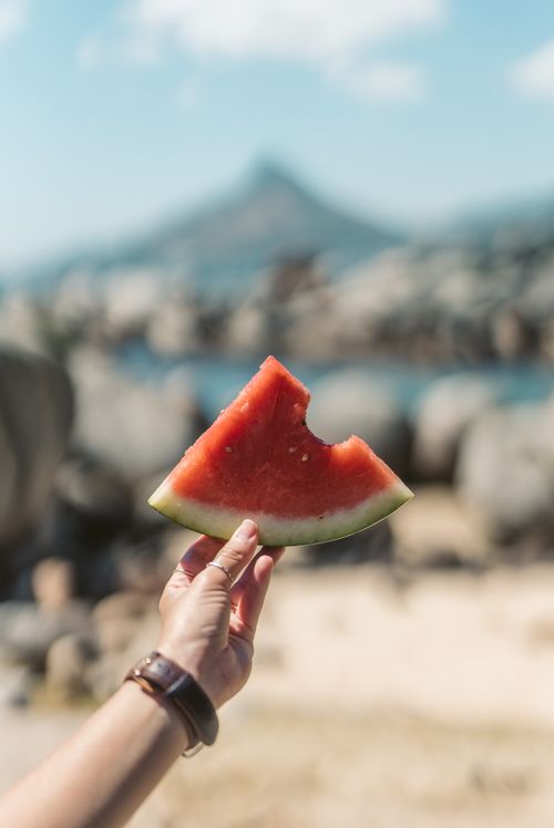 Free Close-up of a hand holding a watermelon slice outdoors with blurred background. Summer vibes. Stock Photo