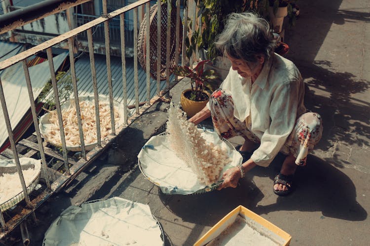 Elderly Woman Winnowing Rice