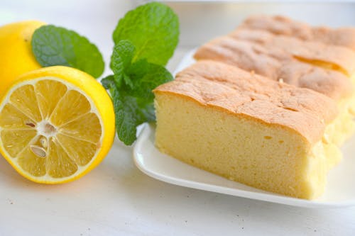 Close-Up View of Sliced Sponge Cake on a Plate beside a Lemon