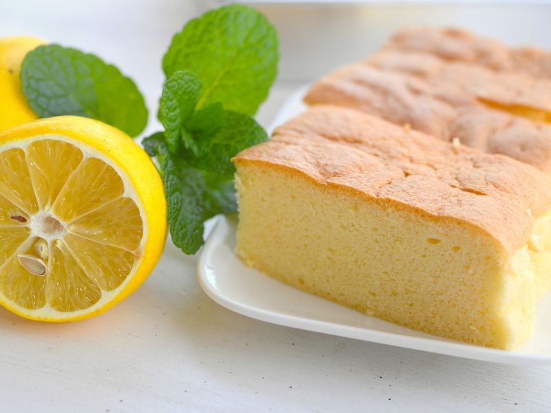 Sliced lemon sponge cake with fresh mint leaves on a white plate.