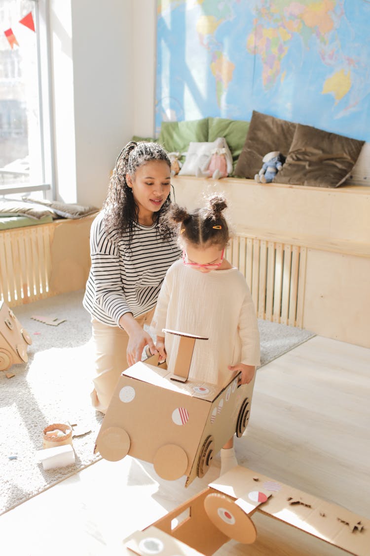 A Woman And A Child Playing With Cardboard Toys