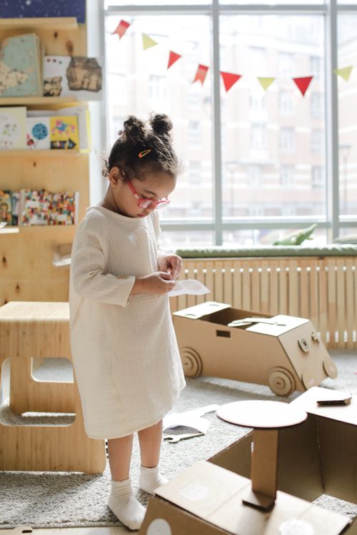 Free Child engaged in creative play with cardboard cutouts, enjoying a sunny day indoors. Stock Photo