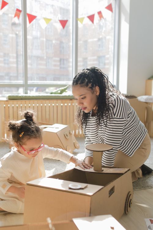 Free A black woman and her preschooler engage in creative cardboard crafting indoors. Stock Photo
