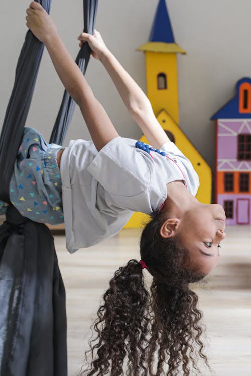 A Girl in White Shirt Riding the Swing in the Playroom