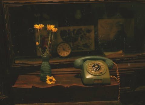Classic vintage setup with rotary phone, sunflowers in vase, and nostalgic decor.