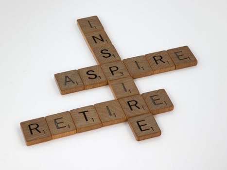 Scrabble tiles on a white surface spell out words inspire, aspire, retire.