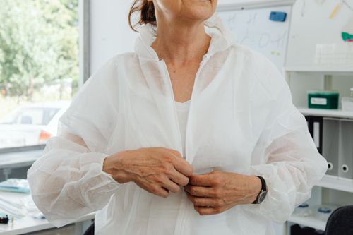 Free An adult in a white protective coverall getting ready for laboratory activities. Stock Photo