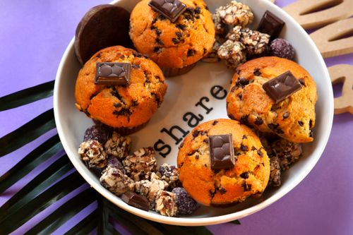 Free Indulge in freshly baked chocolate chip muffins with assorted treats on a decorative plate. Stock Photo