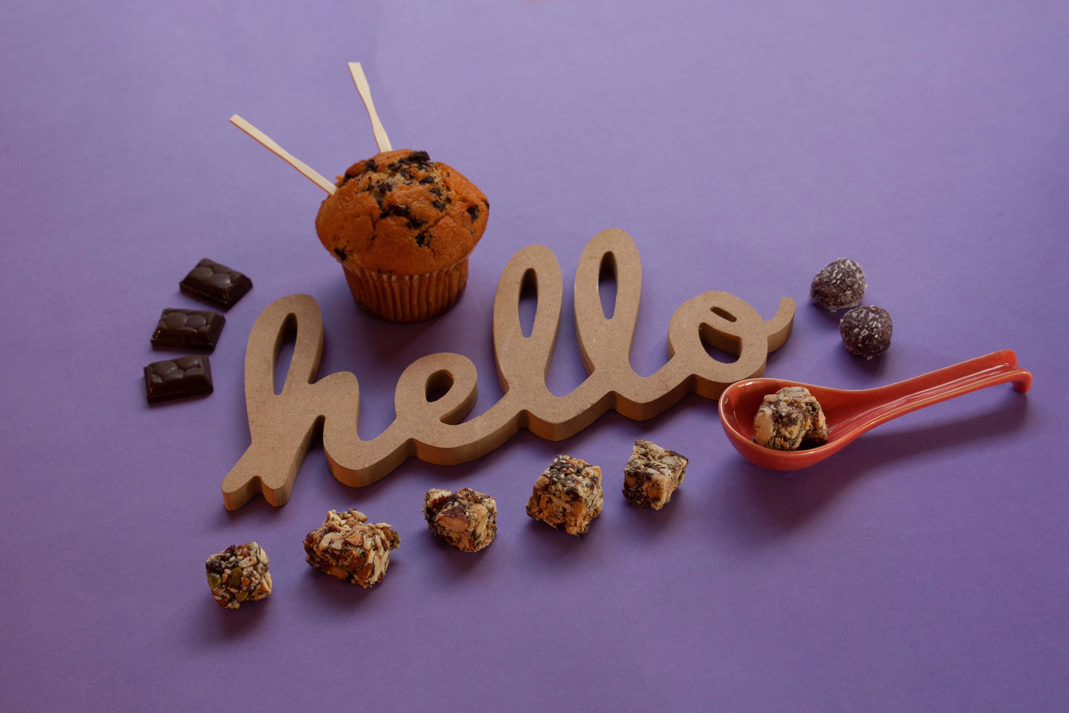 Artistic display of desserts and wooden word 'hello' on a purple surface, perfect for food photography.